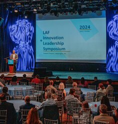 LAF President Michael Grove on stage behind a podium kicking off the symposium