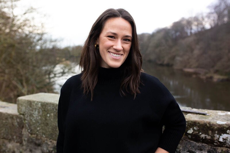 A photo of Betsy Peterson standing in front of a river in winter