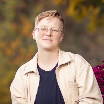 headshot photo of a person in their early 30s with short blonde hair and glasses