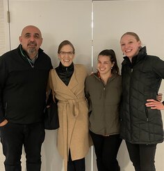 Four people pose in front of conference room doors