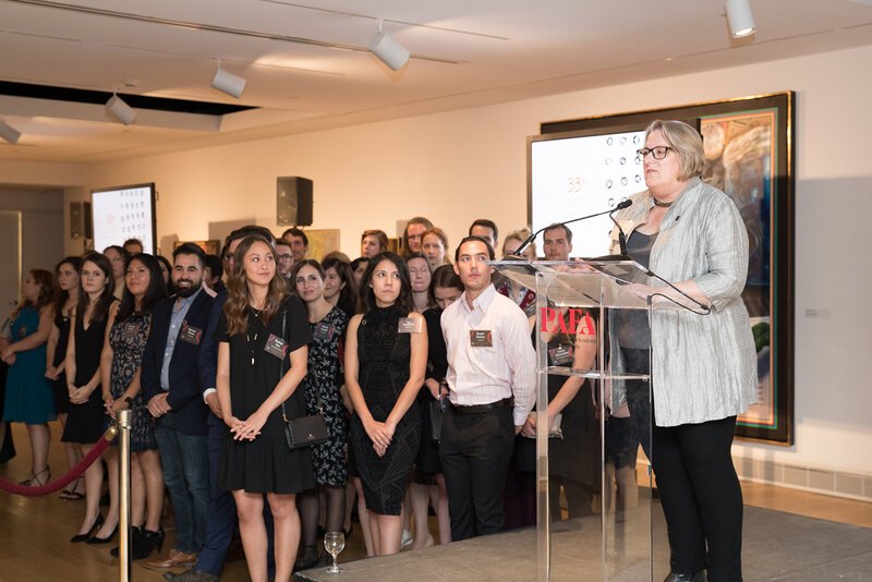 Stephanie Rolley, President of LAF, makes her closing remarks from a podium at the LAF Annual Benefit while a large group of student leaders looks on
